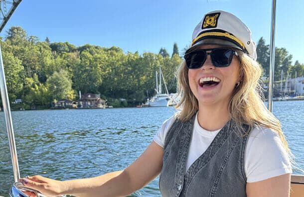 A Chronus colleague laughs at the helm of a boat at a company event