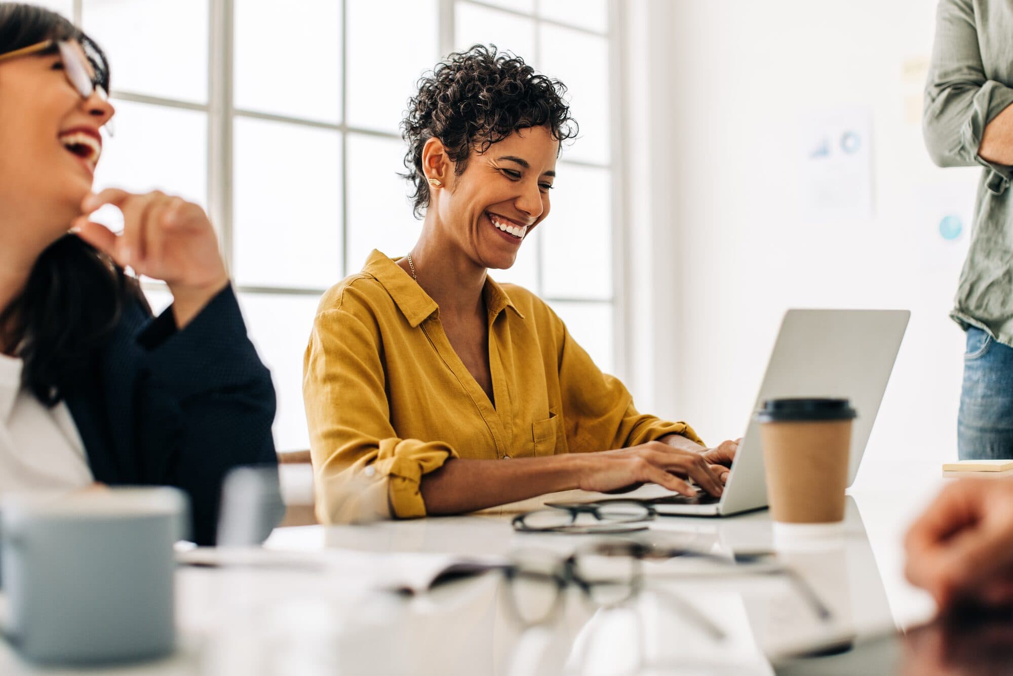 Colleagues laugh together at their desks