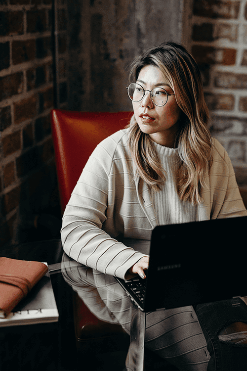 asian woman working on laptop staring at the window
