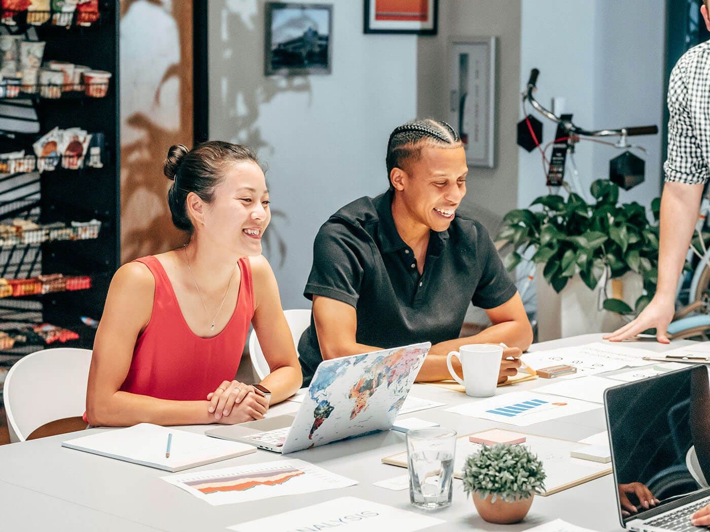 Coaching vs mentoring concept: Smiling coworkers sit together at a conference table