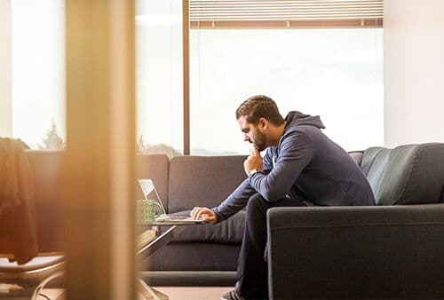 Man sitting on couch during virtual mentoring video call on laptop