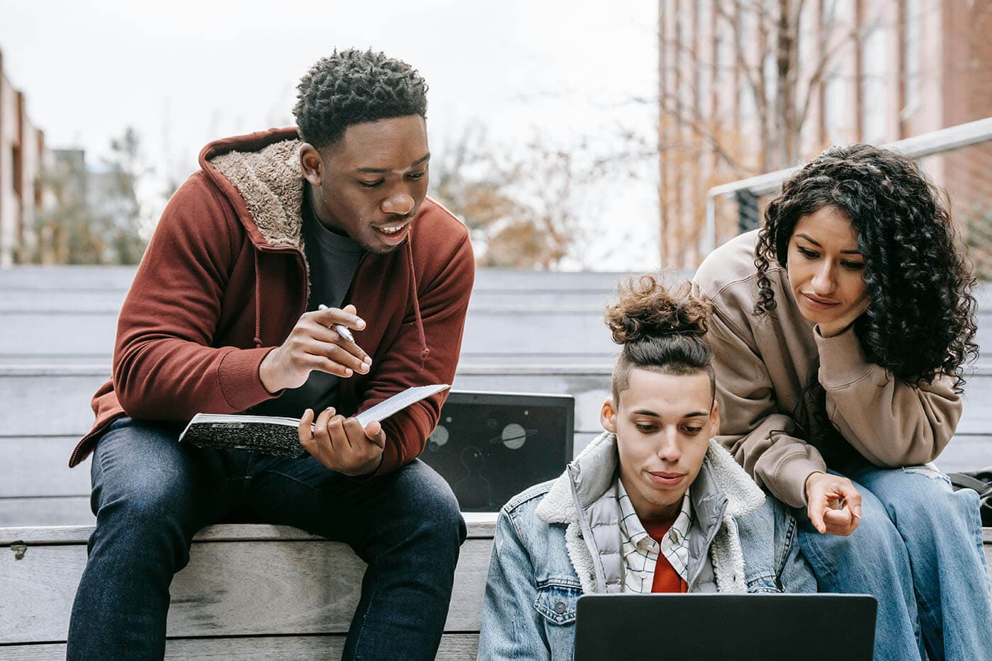 Young colleagues learning together around a laptop outdoors