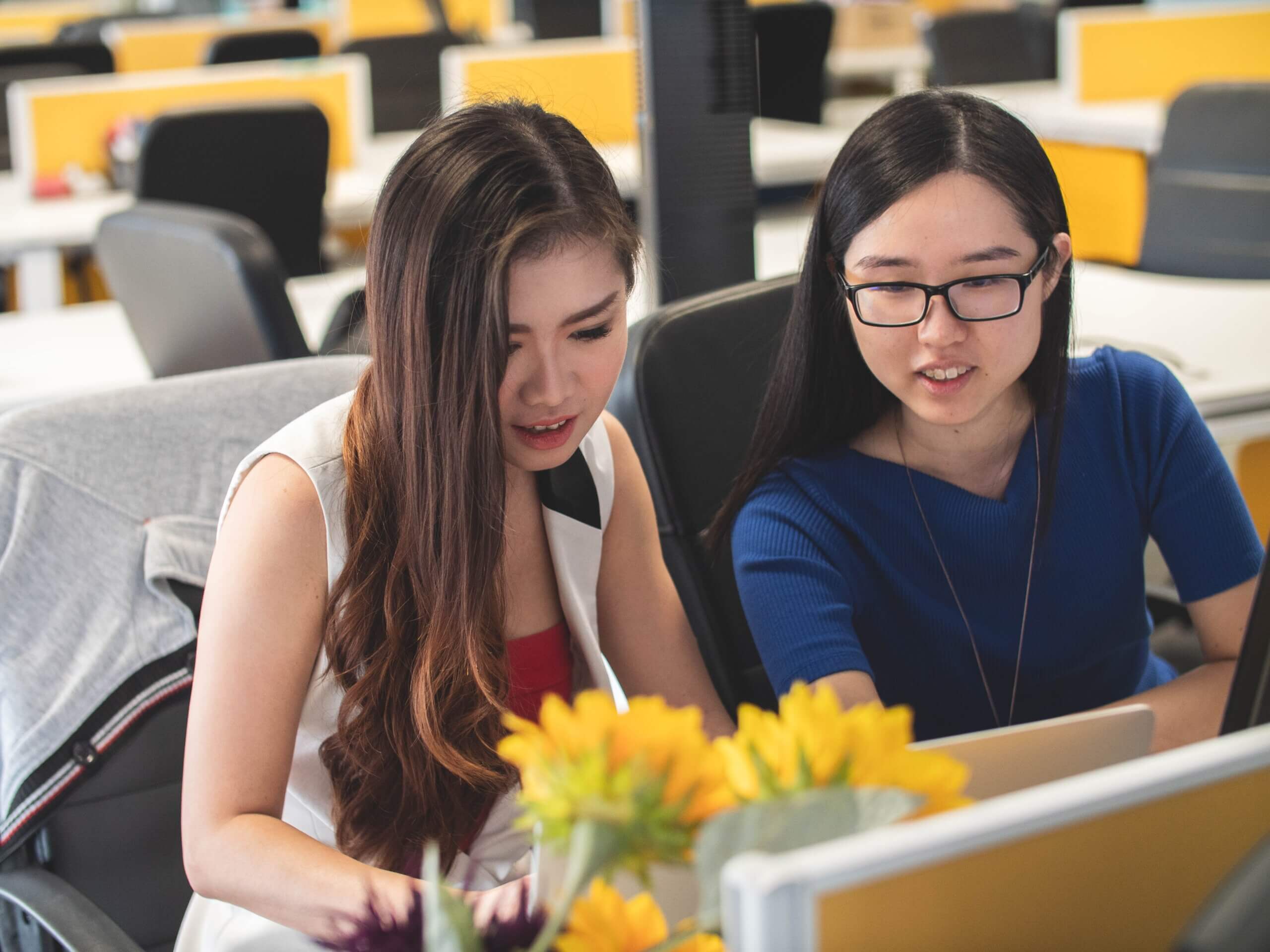 Two employees reviewing work on a computer