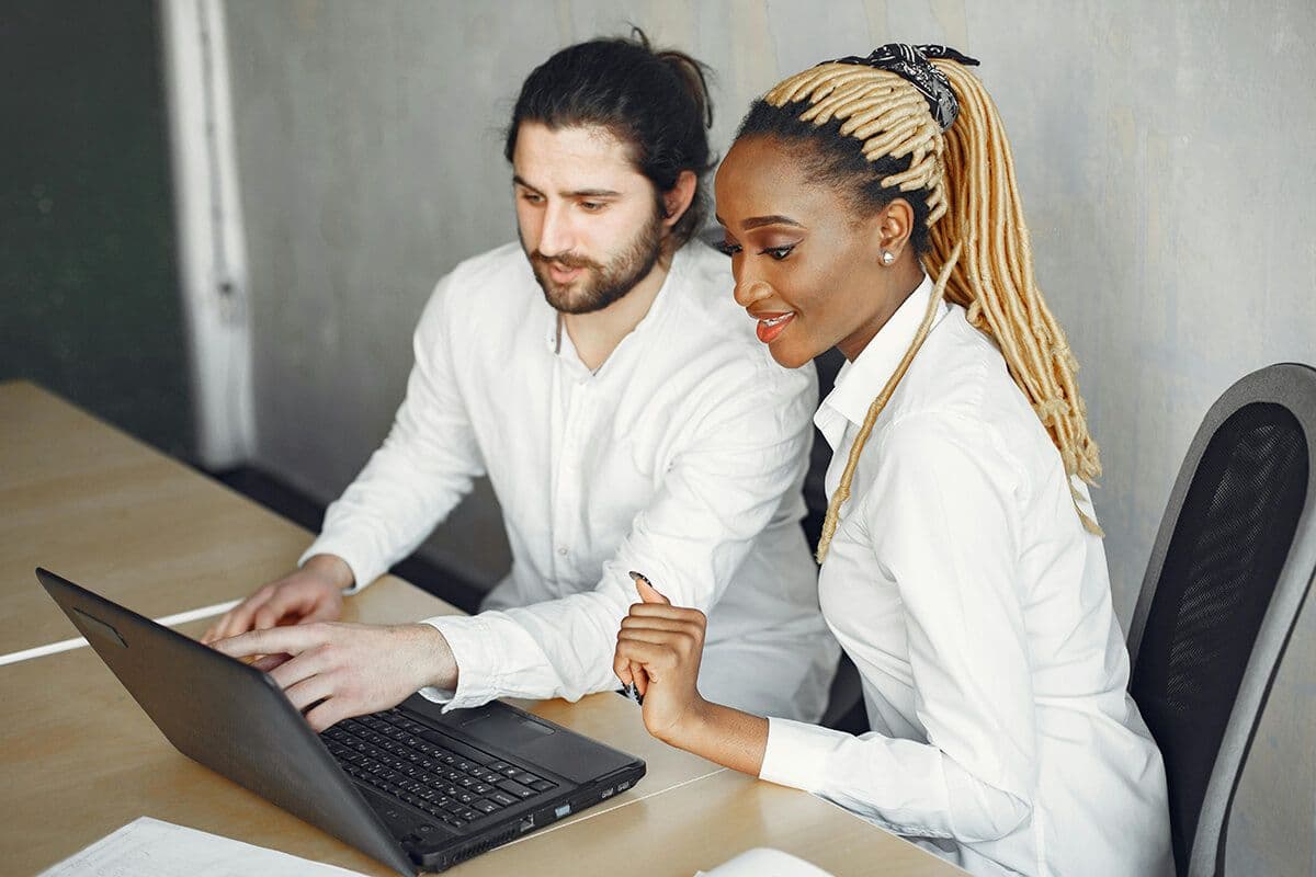 man and woman sitting in front of a laptop during a team mentoring session in the office